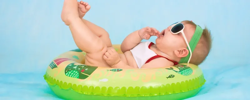 Happy baby in sunglasses lounging in a colorful inflatable ring